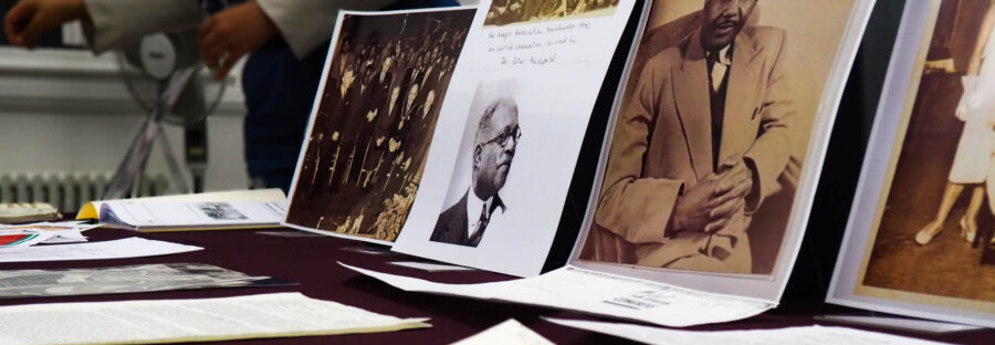 A spread of old sheets of typewritten paper in front of printed historical portraits propped up on a table.