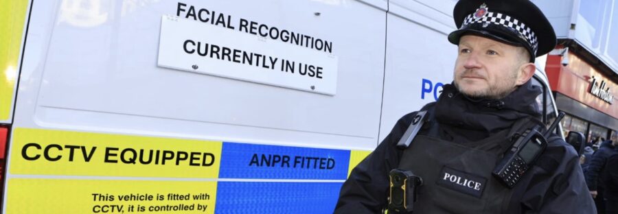 Photo of police officer stood in front of Live Facial Recognition police van.